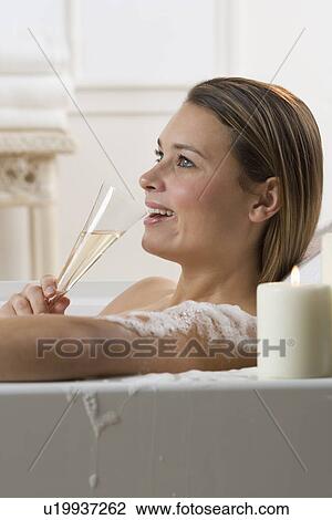 Stock Image - Woman in bathtub drinking champagne. Fotosearch