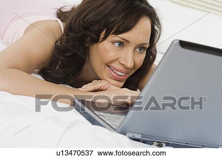 Stock Photo - Woman in bed with laptop computer. Fotosearch