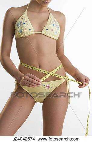 Woman in bikini measuring her waist View Large Photo Image Picture - Woman in bikini measuring her waist. Fotosearch