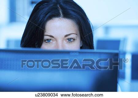Woman in office looking at computer screen View Large Photo Image Picture - Woman in office looking at computer screen. Fotosearch