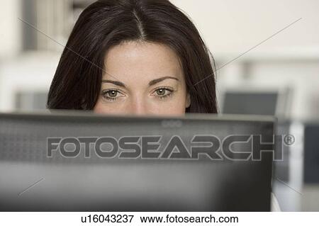 Stock Photo - Woman in office looking at computer screen. Fotosearch