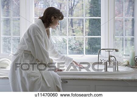 Stock Image - Woman in robe drawing bath. Fotosearch