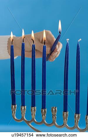 Picture - Woman lighting a Menorah. Fotosearch
