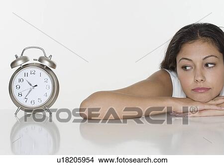 Picture - Woman looking at alarm clock. Fotosearch