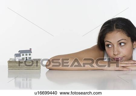 Woman looking at miniature house and money View Large Photo Image Stock Image - Woman looking at miniature house and money. Fotosearch
