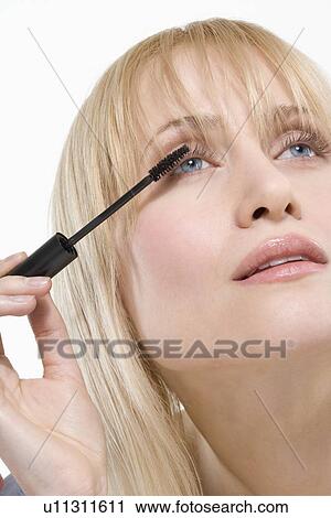 Woman looking up applying mascara View Large Photo Image Stock Image - Woman looking up applying mascara. Fotosearch