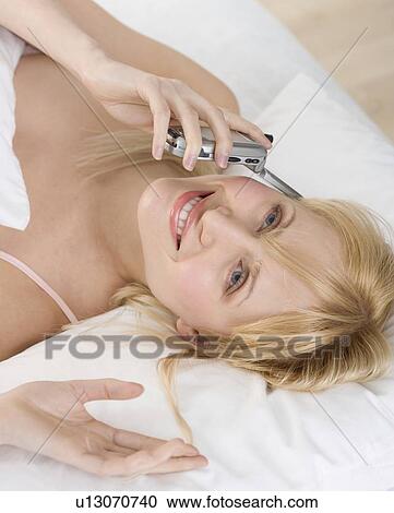 Stock Image - Woman lying down talking on mobile phone. Fotosearch