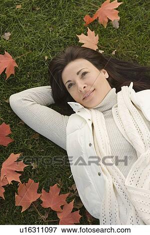 Stock Photo - Woman lying on grass on fall day. Fotosearch