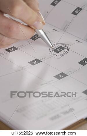 Stock Photography - Woman marking day on calendar. Fotosearch