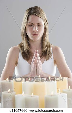 Stock Image - Woman meditating by candlelight. Fotosearch