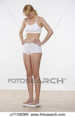 Stock Image - Woman on scale looking down. Fotosearch