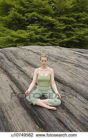 Stock Image - Woman practicing yoga in park. Fotosearch