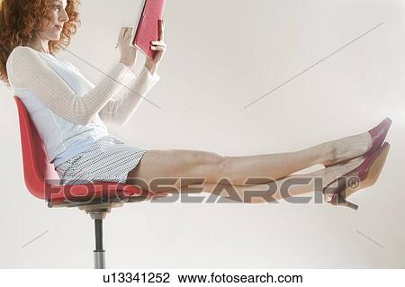 Woman reclining in a chair and holding papers View Large Photo Image Stock Image - Woman reclining in a chair and holding papers. Fotosearch