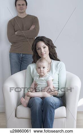 Stock Image - Woman seated with infant and man. Fotosearch