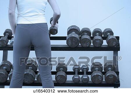 Stock Image - Woman selecting weights. Fotosearch