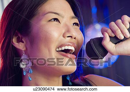 Woman singing into microphone View Large Photo Image Picture - Woman singing into microphone. Fotosearch