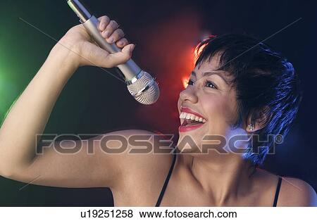 Woman singing into microphone View Large Photo Image Stock Photo - Woman singing into microphone. Fotosearch