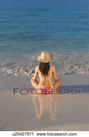 Stock Image - Woman sitting on beach. Fotosearch
