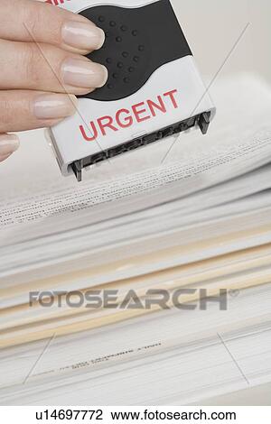 Stock Image - Woman stamping paperwork as urgent. Fotosearch