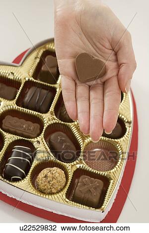 Stock Image - Woman taking a piece of candy from box. Fotosearch