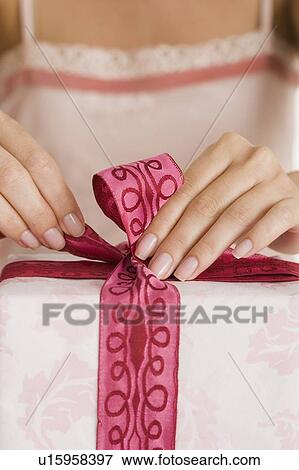 Woman tying ribbon on gift View Large Photo Image Stock Photo - Woman tying ribbon on gift. Fotosearch