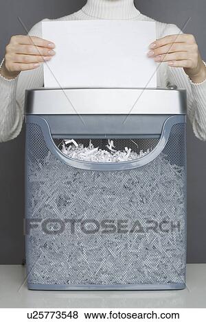 Stock Photo - Woman using a paper shredder. Fotosearch
