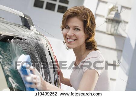 Stock Image - Woman washing car in driveway. Fotosearch