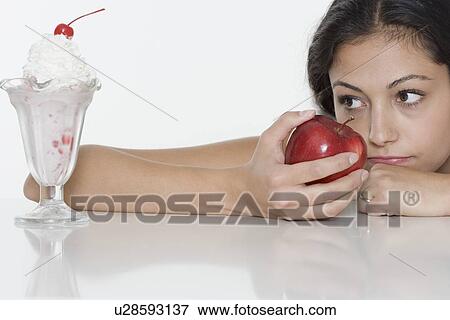 Woman with apple wanting ice cream sundae View Large Photo Image Stock Photo - Woman with apple wanting ice cream sundae. Fotosearch