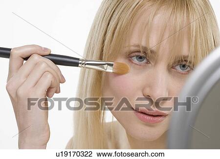 Stock Image - Woman with cosmetic brush and mirror. Fotosearch
