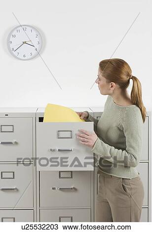 Stock Image - Woman with files looking at clock. Fotosearch