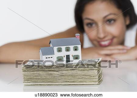 Stock Image - Woman with miniature house and money. Fotosearch
