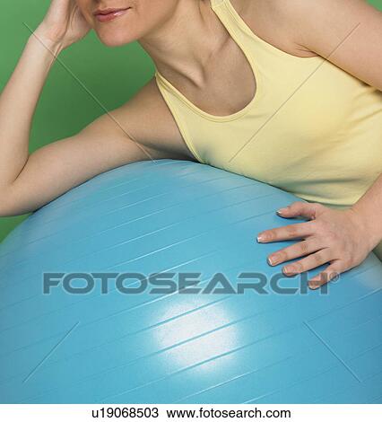 Stock Image - Woman working out with exercise ball. Fotosearch