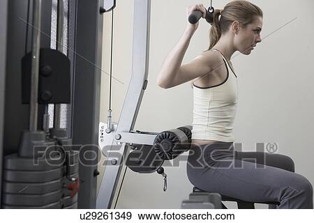 Stock Photo - Woman working with resistance machine. Fotosearch