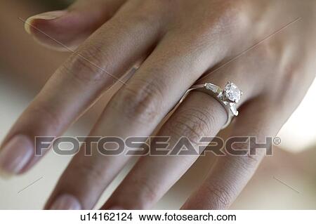 Picture - Woman's hand wearing an engagement ring. Fotosearch