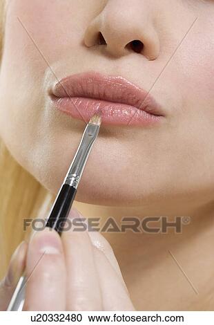 Stock Image - Woman's lips with lipstick brush. Fotosearch