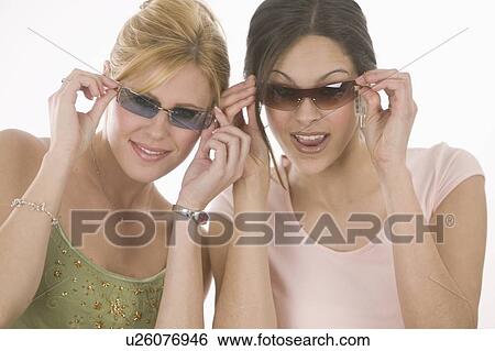Women putting on sunglasses View Large Photo Image Stock Photograph - Women putting on sunglasses. Fotosearch