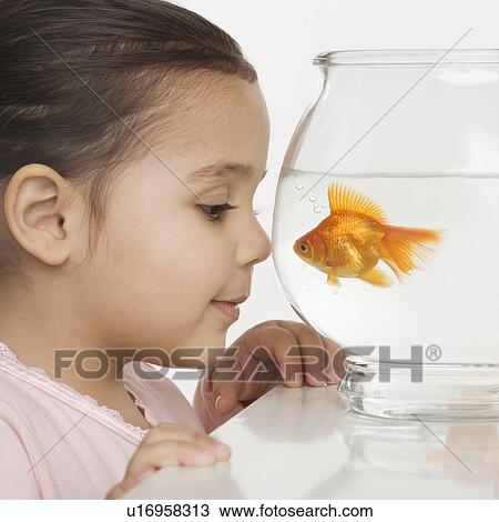 Stock Image - Young girl watching a fishbowl. Fotosearch