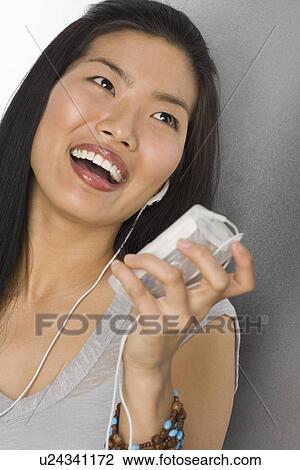 Stock Image - Young woman listening to an MP3 player. Fotosearch