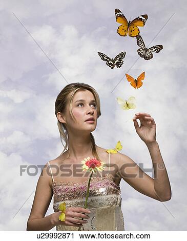 Stock Image - Young woman with flower and butterflies. Fotosearch
