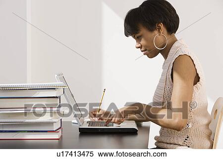 African woman typing on laptop next to stack of books View Large Photo Image Stock Photography - African woman typing on laptop next to stack of books. Fotosearch