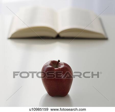 Apple in front of open book View Large Photo Image Stock Photo - Apple in front of open book. Fotosearch