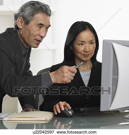 Stock Photo - Asian businessman and businesswoman at computer. Fotosearch