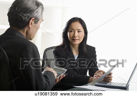 Stock Photo - Asian businesswoman talking to businessman. Fotosearch