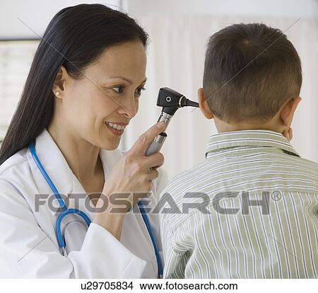 Picture - Asian female doctor examining boy’s ear. Fotosearch