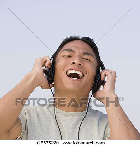 Asian man listening to headphones View Large Photo Image Stock Image - Asian man listening to headphones. Fotosearch