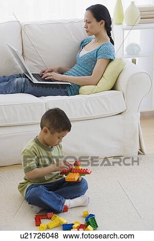 Stock Photo - Asian mother and son relaxing in livingroom. Fotosearch