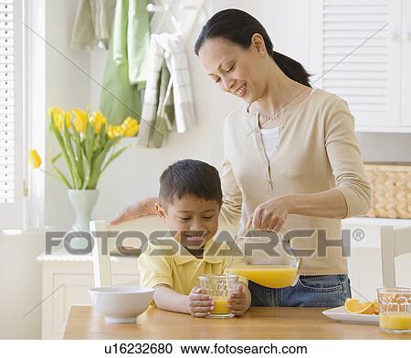 Asian mother pouring juice for son View Large Photo Image Stock Image - Asian mother pouring juice for son. Fotosearch