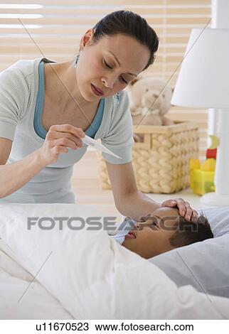 Stock Image - Asian mother taking son’s temperature. Fotosearch