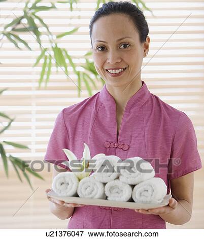Asian woman holding tray of rolled towels View Large Photo Image Stock Photo - Asian woman holding tray of rolled towels. Fotosearch