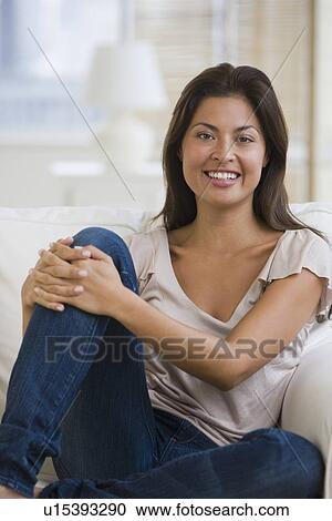 Stock Image - Asian woman sitting on sofa. Fotosearch